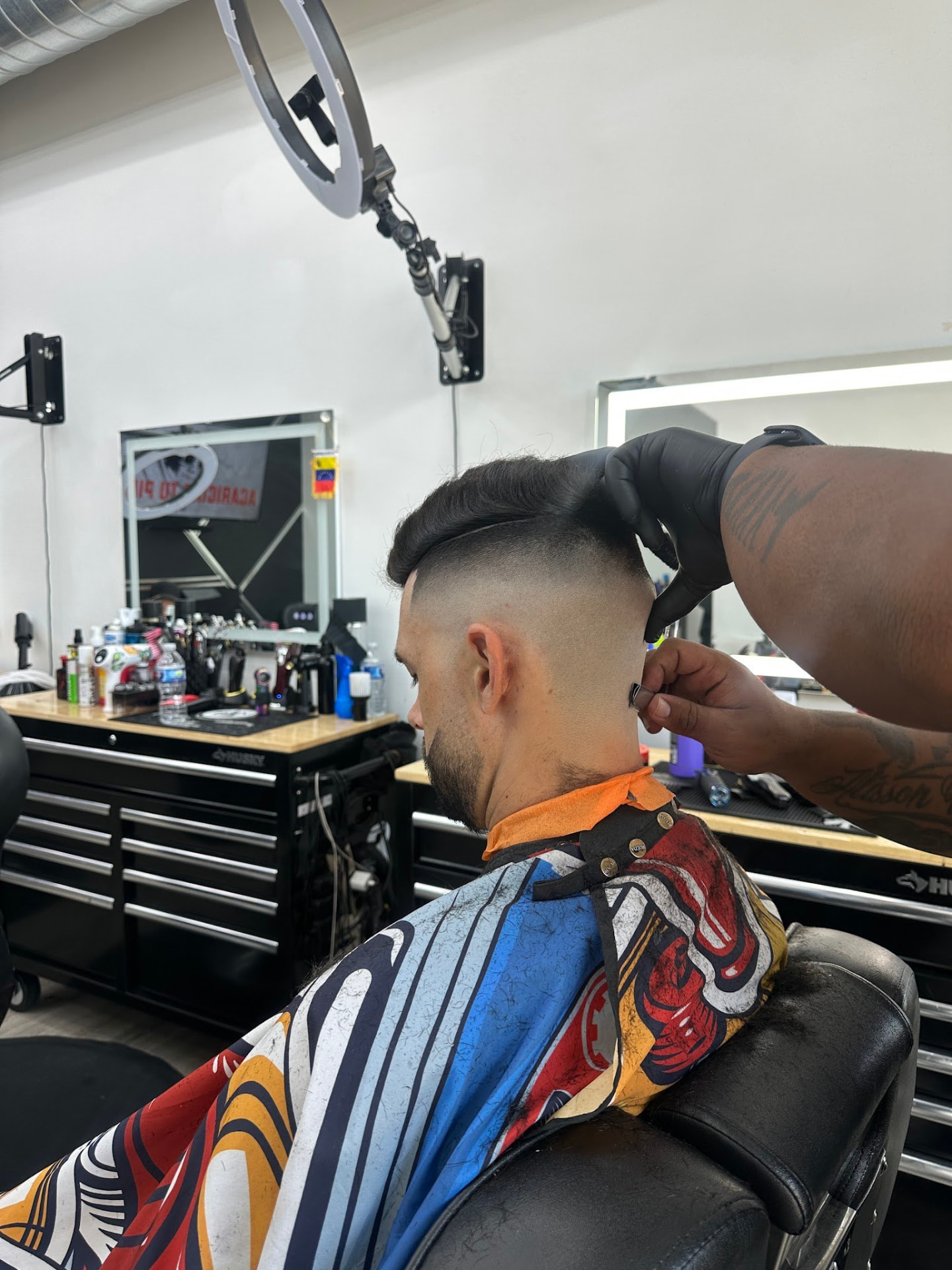 Barber shaping a high skin fade with a comb over